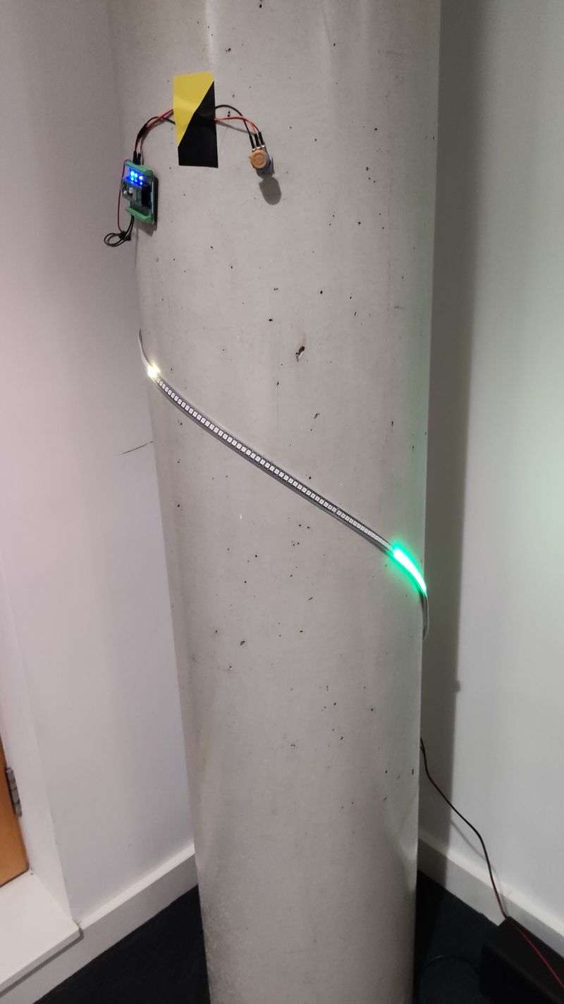An led strip is taped to a pillar with hazard tape, and some leds are visibly lit up. A small knob is taped near the middle of the pillar.