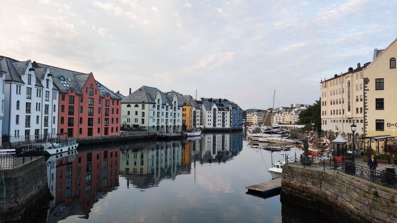 A picturesque view of sailing boats moored alongside buildings in the Jugendstil, on a grey and cloudy day