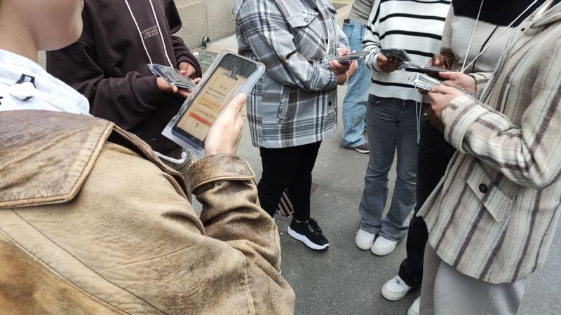 Outdoors, a group of audience members answer some questions using the phones