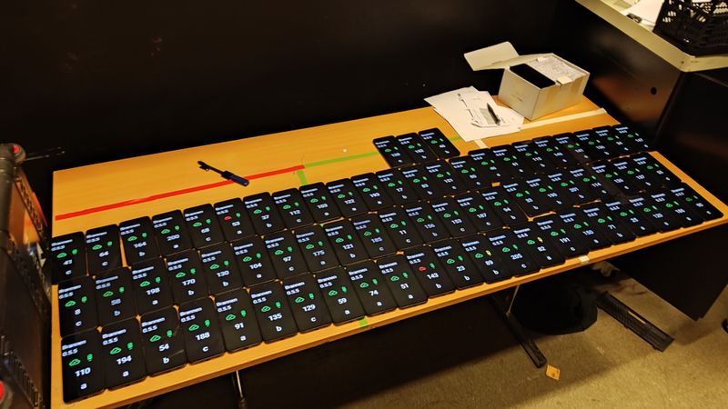 A table, completely covered with dozens of phones being set up for the show