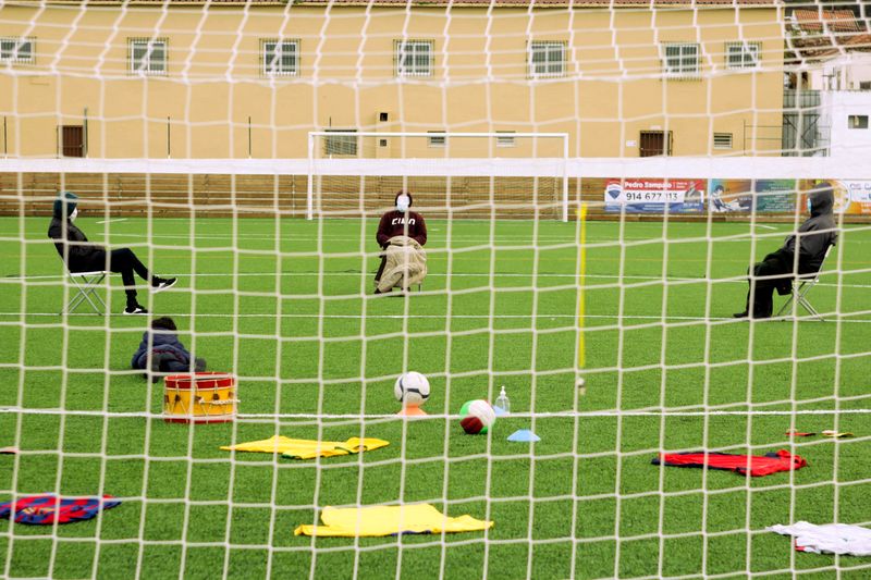 Photograph of four actors sat in a football field, rehearsing for the show