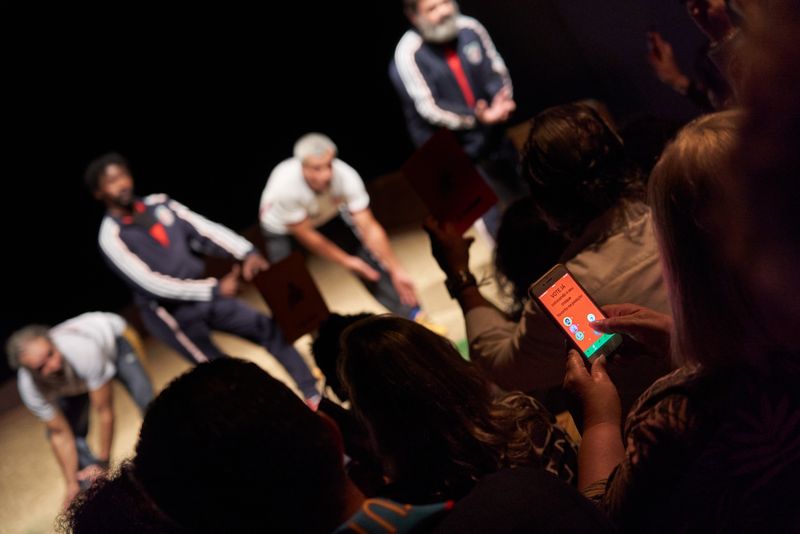 Photograph of an audience member using the phone app to vote on the substitution