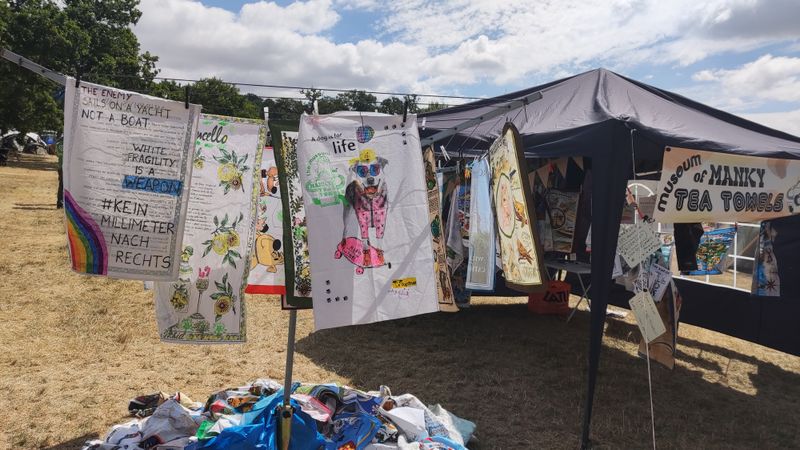 A collection of tea towels on washing lines in and around a marquee. In the middle a sign states 'museum of manky tea towels'