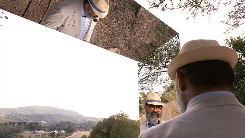 Photograph of an actor wearing a tan suit and hat, reflected at different angles through a squared mirror frame in a rural setting.